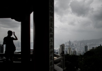 Китай, Гонконг, 17 липня 2014 року. Жінка дивиться на панораму міста у грозу. Тайфун Рамасун пронісся регіоном, забравши щонайменше 13 життів у Філіппінах. Фото: AFP