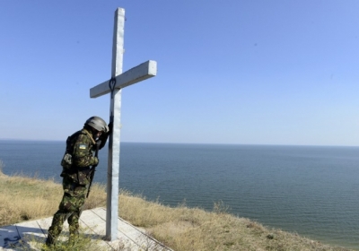 Україна. Військовослужбовець батальйону "Діва Марія" молиться біля хреста, встановленого на березі моря поблизу Маріуполя, 2 жовтня 2014. Фото: АFР