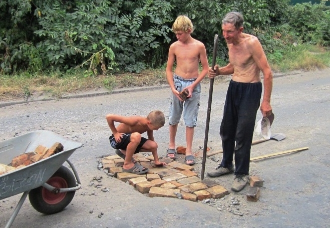 Діти на Донбасі ремонтують цеглою дорожні ями (фото)