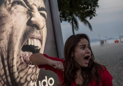 Бразилія, Ріо-де-Жанейро, 26 червня 2014 року. Футбольні вболівальники у Бразилії фотографуються із постером гравця збірної Уругвая Луїса Суареса. Футболіст вкусив за плече італійського захисника Джорджо К