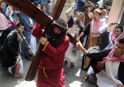 Филиппины, Манила. Человека, который играет роль Иисуса Христа бьют, в то время как он несет деревянный крест. Это театрализвоанное шествие является частю популярного ритуала искупления грехов. Фото: AFP