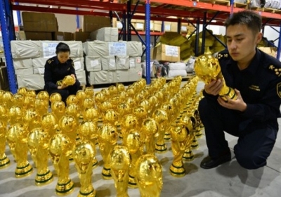 Китай, Иу, 16 апреля 2014 года. Полиция Китая конфисковала более 1 тыс поддельных кубков ФИФА к футбольному чемпионату Евро 2020 года, окрашенных золотой краской. Груз обнаружили, когда он ожидал экспорта в Ливию. Фото: AFP