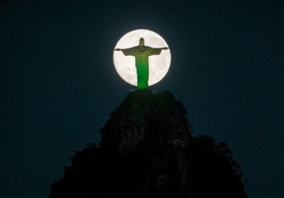 Бразилія, Ріо-де-Жанейро, 13 липня 2014 року. Статуя Христа у Ріо з ілюмінацією у кольорах бразильського прапору на тлі місяця. Впродовж вихідних мешканці Землі могли спостерігати незвично великий і яскравий "супер-місяць". Фото: AFP