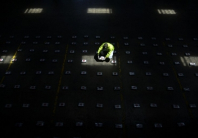 КОЛУМБИЯ: Колумбийский полицейский раскладывает пакеты кокаина, 27 сентября 2014, в городе Медельин. Отдел по борьбе с наркотиками национальной полиции изъяли полторы тонны кокаина во время операции под названием "Республика 69". Фото: АFР