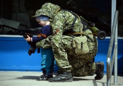 Украина, Константиновка, 28 апреля 2014. Человек в камуфляже фотографируется с ребенком перед зданием горсовета, который в ночь на 28 апреля захватили пророссийские сепаратисты. Фото: АFР
