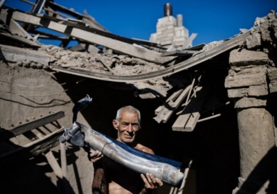 УКРАИНА, Оленевка: 20 августа 2014, мужчина держит кусок ракеты в его разрушенном доме. Фото: АFР