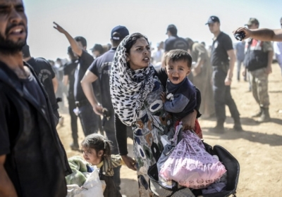 ТУРЦИЯ: женщина пересекает границу между Сирией и Турцией на юго-востоке города Суруч 23 сентября 2014 Агентство по делам беженцев ООН предупредило, что более 400 тысяч человек могут бежать в Турцию с курдского региона в Сирии. Фото: АFР
