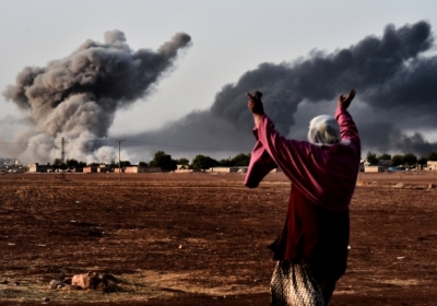 Жінка реагує на те, як дим піднімається у сирійському місті Айн-аль-Араб, яке курди називають Кобане, після атаки від коаліції США. Це вигляд з сирійсько-турецького кордону. 13 жовтня, 2014.    Фото: АFР