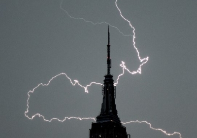 США, Нью-Йорк, 3 липня 2014 року. Блискавка над шпилем Empire State Building у Нью-Йорку. На східному узбережжі США тривають зливи і грози, які приніс тропічний шторм Артур. Фото: AFP