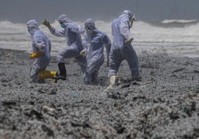 Люди у захисних костюмах серед сміття, що вимило на берег із судна, що загорілось, Коломбо, Шрі-Ланка, 27 травня 2021 року Фото: AP Photo/Eranga Jayawardena