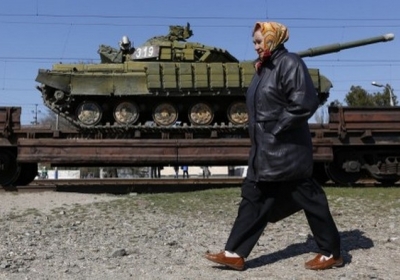 Симферополь: Женщина проходит мимо эшелона украинских танков, которые вывозят из Крыма 31 марта 2014. Фото: AFP